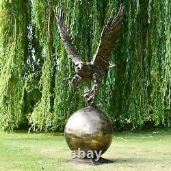 Grand aigle doré sur sculpture de jardin en forme de boule en aluminium ornant l'extérieur